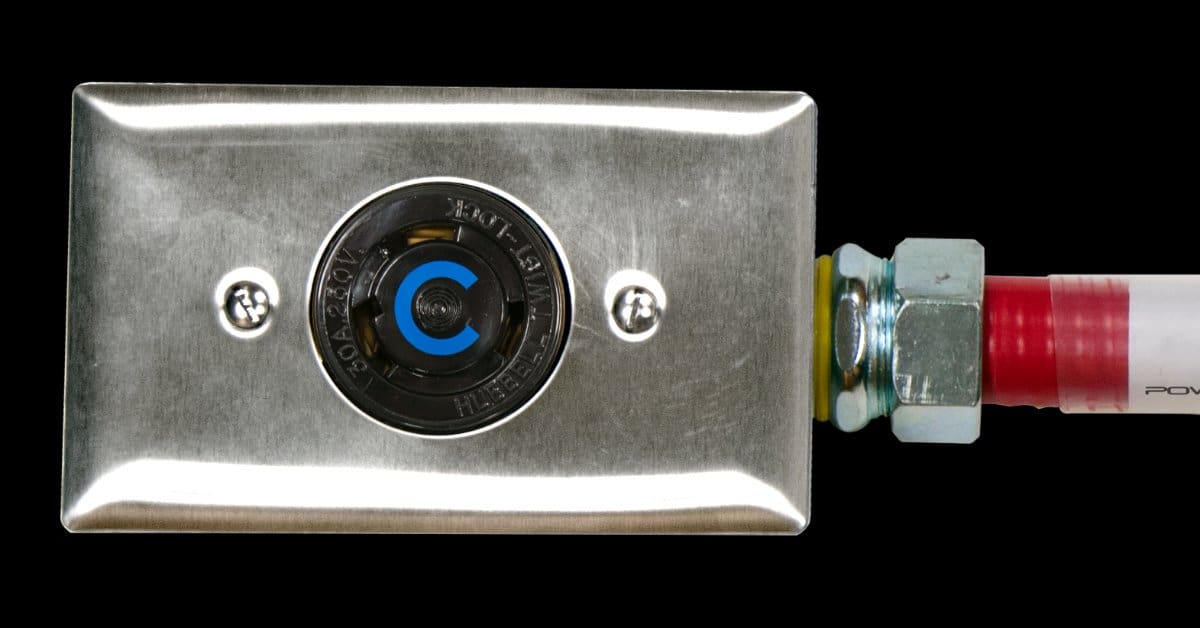 Close-up of a stainless steel industrial power outlet connected to a flexible red conduit, isolated on a black background.