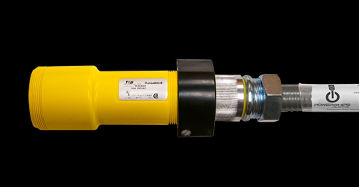 The side of a yellow industrial plug connects to a Russellstoll receptacle through a dark collar on a black background.