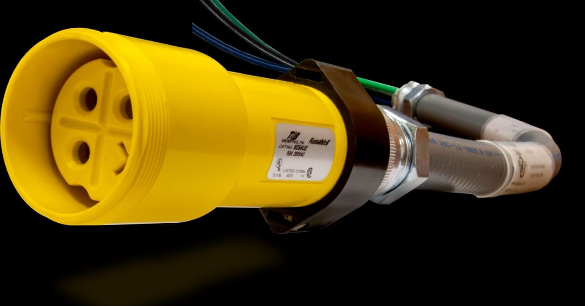 Colored wires feed into a gray conduit behind a forward-facing yellow industrial Russellstoll plug on a plain background.
